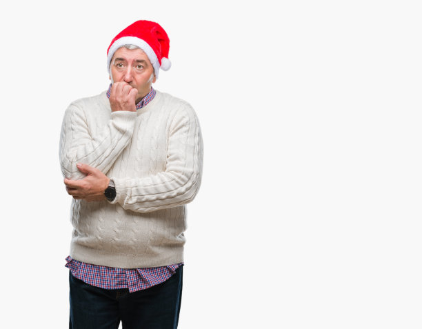 英俊的老人戴着圣诞帽在孤立的背景看起来紧张和紧张的手在嘴咬指甲。焦虑的问题。图片下载