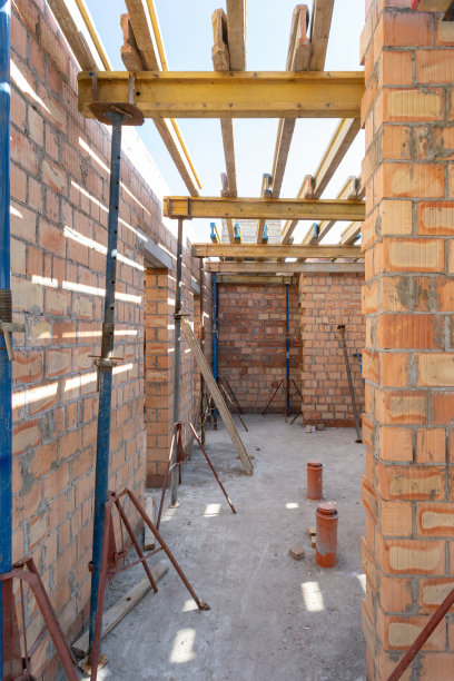 模板施工的概念。垂直照片未完工的建筑与屋顶下的木板和金属支撑管道图片下载