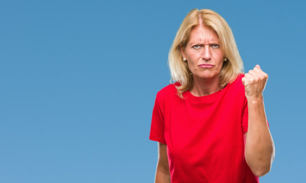中年金发女人在孤立的背景愤怒和疯狂举起拳头，沮丧和愤怒，而大喊与愤怒。愤怒和侵略性的概念。图片下载