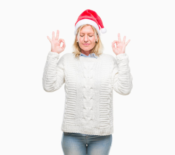 中年金发女人戴着圣诞帽在孤立的背景放松，微笑着闭上眼睛做冥想手势与手指。瑜伽的概念。图片下载