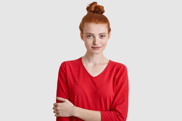 有魅力的女人的照片红头发，保持手在胸部，穿着休闲衣服，有雀斑的皮肤，孤立在白色的背景。室内漂亮的年轻模特。人与美的概念图片下载