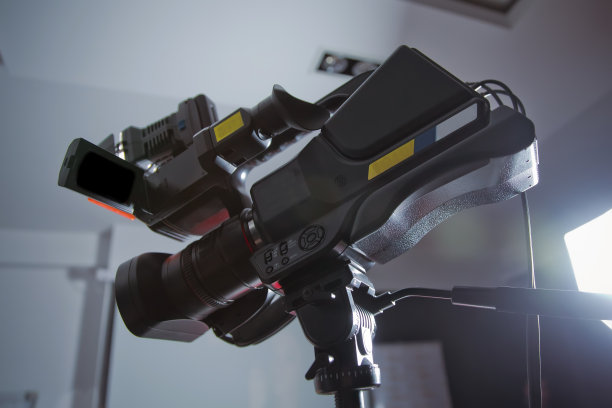 三脚架上配有麦克风的专业数码无反光镜摄像机拍摄视频。三脚架上的数码摄像机侧视图。用摄像机拍摄事件。——图片图片下载