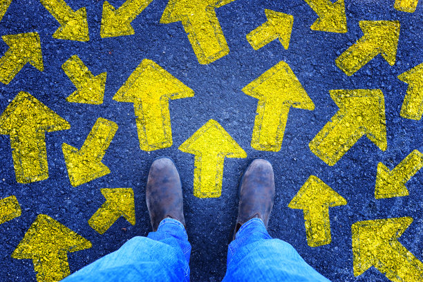 俯视图照片的人在牛仔裤和复古的鞋子站在沥青路面与绘制箭头显示不同的方向。过滤掉。图片下载