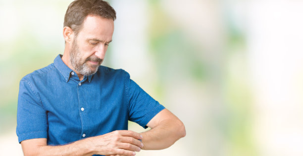 英俊的中年优雅的高级男子过孤立的背景，检查手表上的时间，轻松和自信图片下载