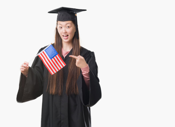 年轻的中国妇女穿着研究生制服，手和手指很高兴地指着美国国旗图片下载