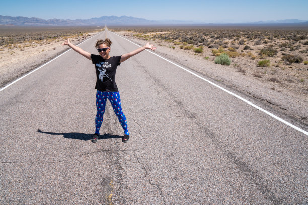 成年女子举起双臂站在道路中间(内华达沙漠中的外星公路)。理念为胆大、不怕死、敢闯、开路图片下载