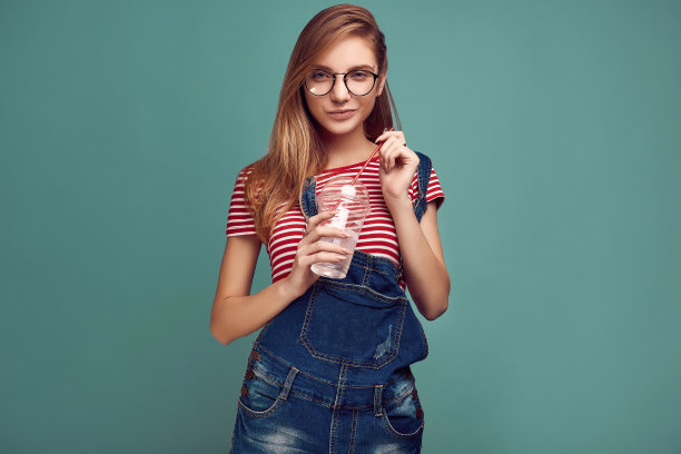 可爱的少女穿着牛仔工装裤，戴着苏打水眼镜图片下载