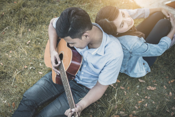 情人节概念，情侣坐在公园里弹吉他图片下载