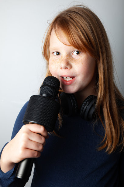 拿着麦克风的胖女孩边唱边笑。白色背景上的肖像图片下载
