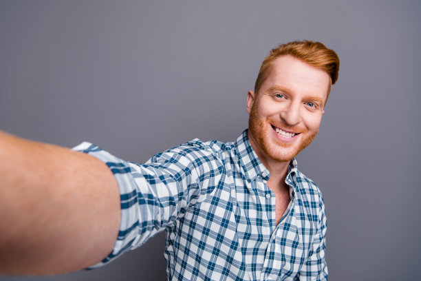 好的积极愉快愉快有趣英俊有吸引力的时髦男人的自画像穿着格子衬衫孤立在灰色柔和的背景图片下载
