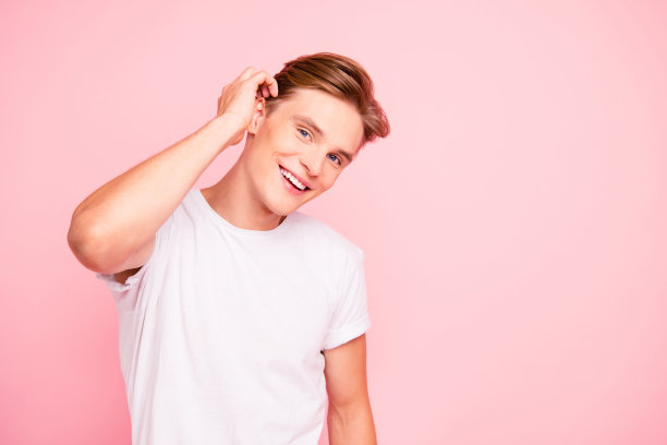 漂亮可爱的可爱的有吸引力的英俊的整洁的愉快的愉快的家伙在白色t恤触摸修复头发孤立在粉红色柔和的背景图片下载