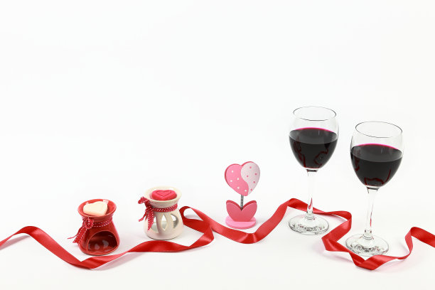 情人节的概念。两杯红酒配上心形蜡烛和红色丝带，背景是孤立的白色。图片下载
