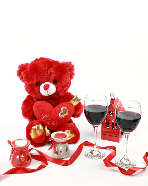 情人节的概念。红色泰迪熊与红酒和心形蜡烛与红丝带在孤立的白色背景。图片下载