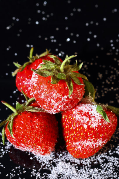 熟透的有机草莓，加砂糖，涂在黑玻璃上图片下载
