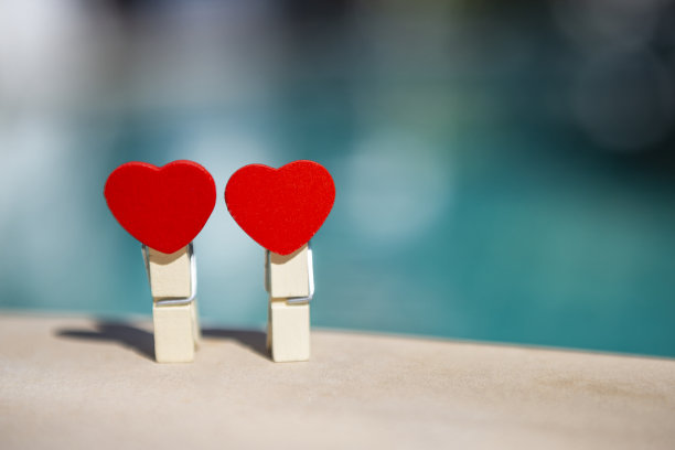 两个木制的红色心形剪辑模糊的蓝色背景，情人节概念背景图片下载