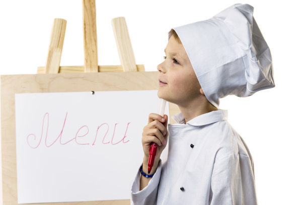 穿着厨师服的可爱男孩在纸上准备菜单图片下载