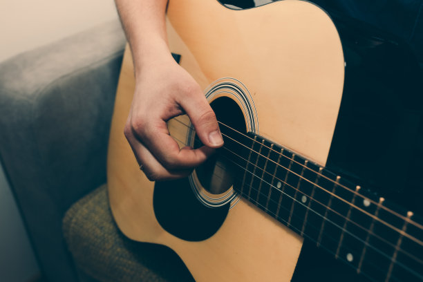 家里的男人正在弹吉他。大家的手在弦上拨动和弦。音乐创造生活理念。每个人的业余爱好。复古的吉他照片。图片下载