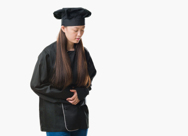 年轻的中国女子在孤立的背景下穿着厨师制服，手放在胃上，因为消化不良，痛苦的疾病感觉不舒服。疼痛的概念。图片下载