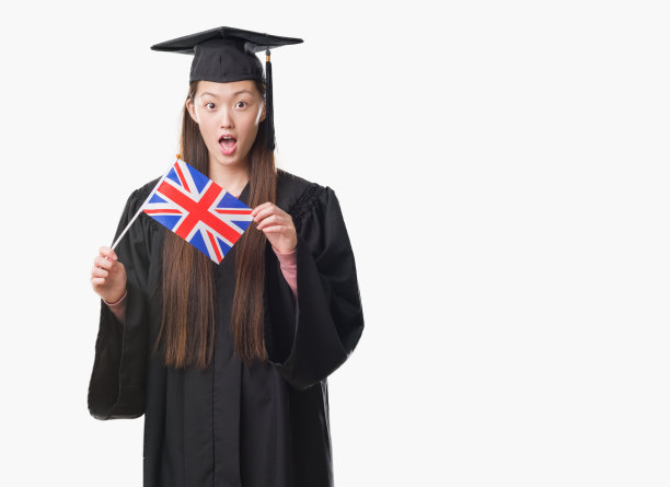 年轻的中国女子穿着研究生制服，举着英国国旗，脸上带着震惊，害怕和兴奋的恐惧表情图片下载