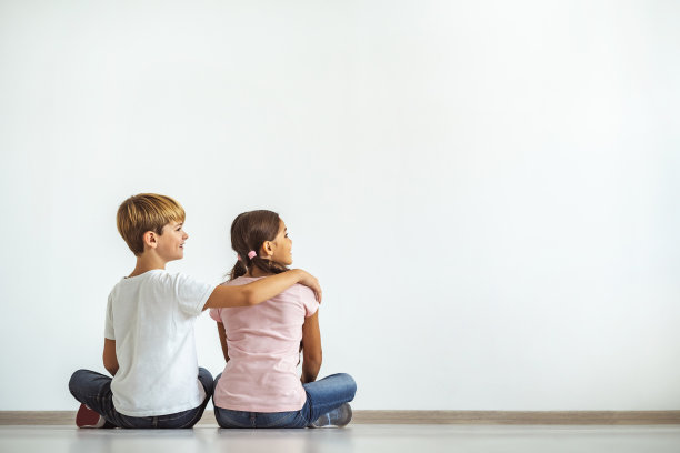 在白色的墙壁背景上，快乐的男孩拥抱着一个女孩图片下载