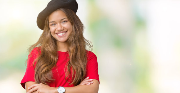 年轻美丽的黑发时尚女人穿着红色的t恤和黑色贝雷帽在孤立的背景快乐的脸微笑，双臂交叉看着镜头。积极的人。图片下载