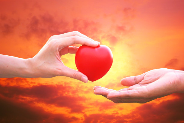 朋友的手给红心以夕阳的天空背景鼓励失败者图片下载