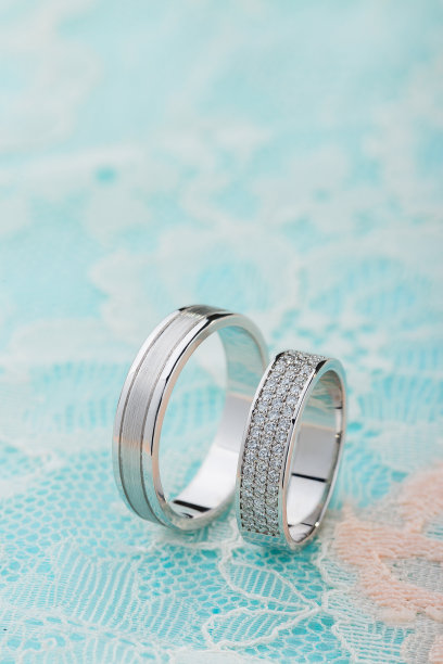 一对白金结婚戒指与钻石在蓝色蕾丝背景图片下载