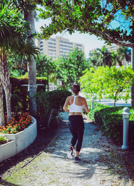 在绿荫遮蔽的城市小路上跑步锻炼的妇女图片下载