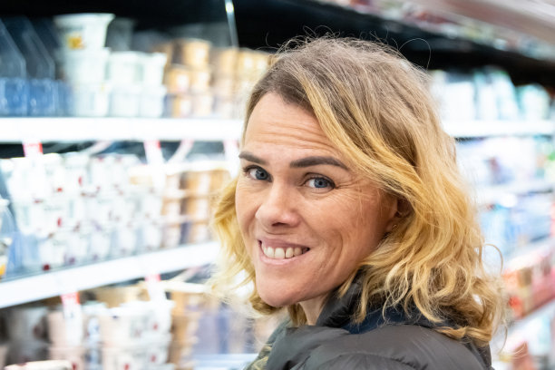 成熟的金发女人在超市货架前摆姿势(真人)图片下载