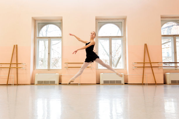 少女芭蕾舞演员在大型舞蹈工作室练习芭蕾舞动作图片下载