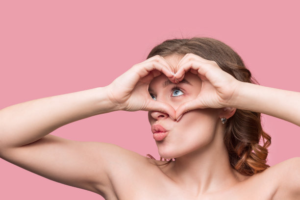 漂亮的年轻微笑的女人，长长的波浪般的秀发，自然的妆容看着镜头图片下载