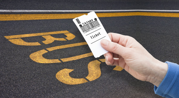 巴士文字写在黄色在一个黑暗的沥青与一个女性的手持有巴士票-旅游巴士概念图像与复制空间图片下载