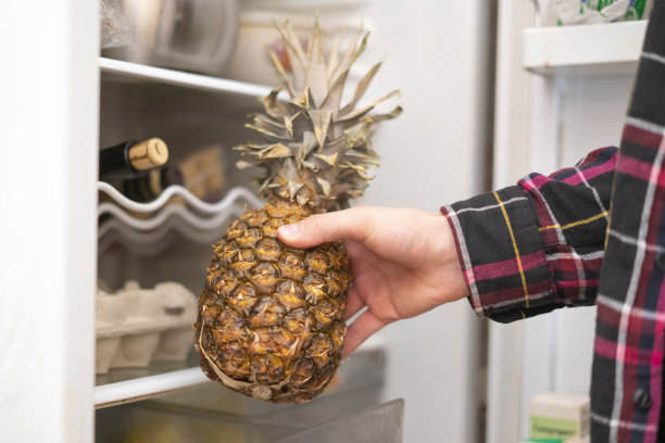 近距离照片的人把水果，西红柿，橙子和菠萝在冰箱图片下载