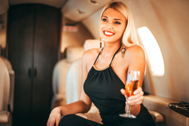 美丽的金发模特喝香槟，微笑，享受自己的私人飞机出差图片下载