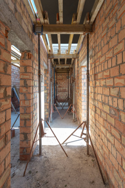 模板施工的概念。垂直照片未完工的建筑与天花板支撑元素，屋顶下的木梁和金属支撑管道图片下载