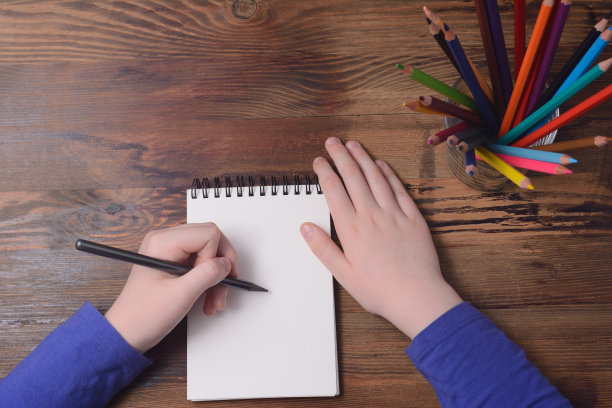 左手拿着铅笔，木板上放着笔记本图片下载