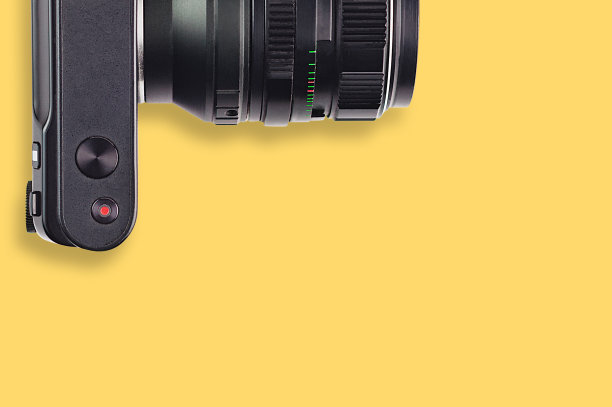 黄色桌子上的黑色专业数码相机。为你的文本复制空间。前视图。旅行或视频博客的概念图片下载