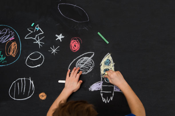 那孩子在黑板上画了一个火箭和空格。学前儿童在家里的创造力。图片下载
