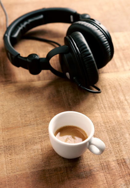黑色耳机和一杯咖啡，背景是质朴的木头。副本的空间。图片下载