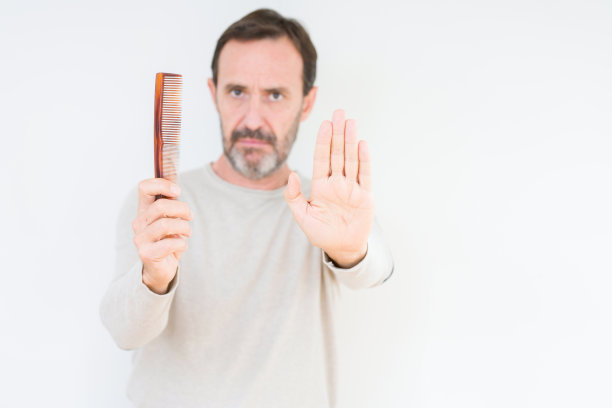 高级男子拿着头发梳在孤立的背景与开放的手做停止标志与严肃和自信的表情，防御手势图片下载