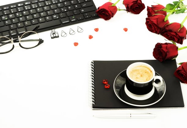 女士的办公桌俯视图。女性的工作空间，笔记本电脑，鲜花，红玫瑰，配件，眼镜，一杯咖啡在白色的背景。平躺女性背景。本空间图片下载