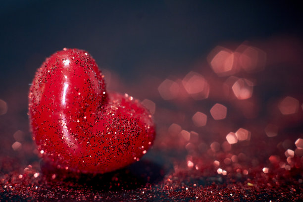 红色小心与抽象的散景在黑色的背景图片下载