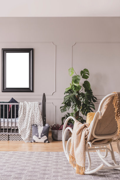 在灰色儿童卧室的摇椅上的毯子，床上有海报的模型。真实的照片图片下载