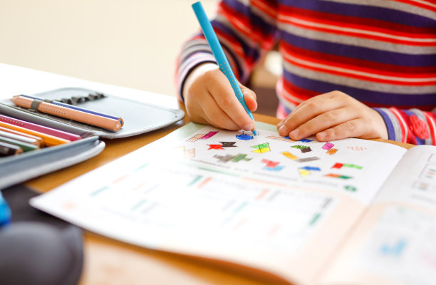 快乐微笑的小男孩在学校开始前的早上在家做作业。小孩子在室内做运动。小学及教育:男孩画几何图形图片下载