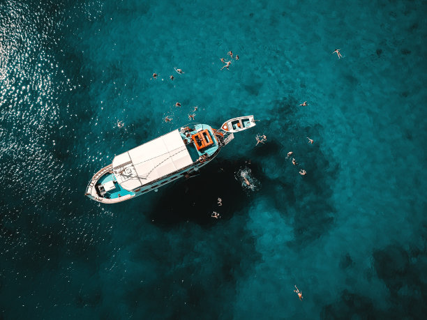 航拍美丽的蓝色泻湖在炎热的夏日与帆船。俯视图的人游泳周围的船。图片下载