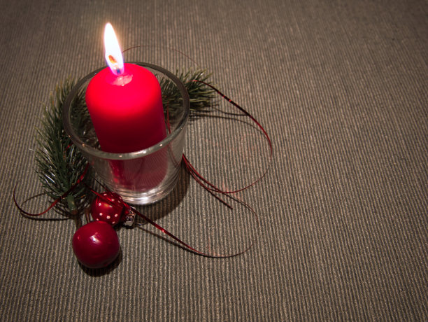 桌上一只玻璃杯里燃着的蜡烛图片下载