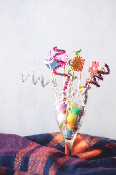 节日明亮的装饰和闪亮的雪花在酒杯酒杯在紫色温暖的羊毛围巾。冬季圣诞假期垂直背景。图片下载