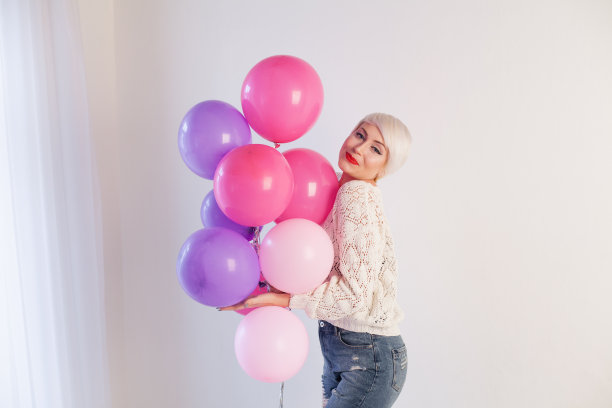 漂亮的金发女人带着礼物和气球来度假图片下载