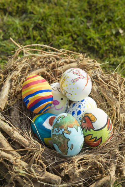 在一个阳光明媚的日子里，将不同形式、卡通和色彩鲜艳的复活节彩蛋放在户外的鸟巢里图片下载