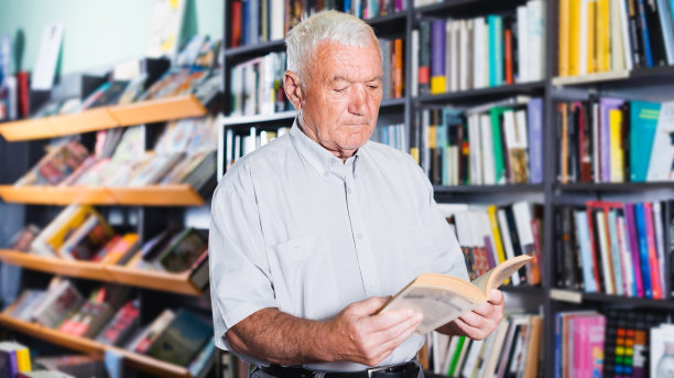 这位老人正在挑选空闲时间阅读的书图片下载